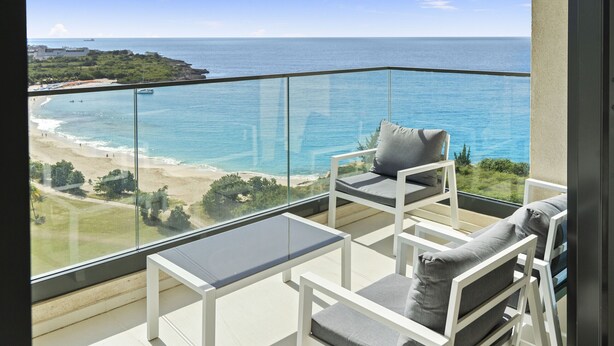 A balcony with a glass railing overlooking a beach and the sea. - A1302 (Cupecoy)