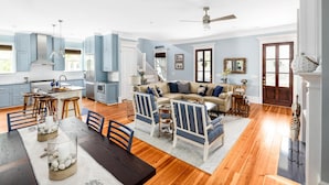 A spacious living room with a sofa, a dining table with chairs, and a kitchen area with cabinets and a stove. - Family-Friendly Wild Dunes Home Just Steps from the Beach (Isle Of Palms)