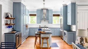 A modern kitchen with blue cabinets, wooden flooring, and a central island with stools. - Family-Friendly Wild Dunes Home Just Steps from the Beach (Isle Of Palms)