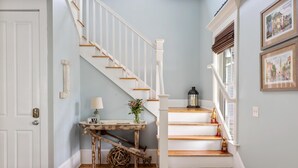 A staircase with white railings and wooden steps, a small table with a lamp, and a decorative ball. - Family-Friendly Wild Dunes Home Just Steps from the Beach (Isle Of Palms)