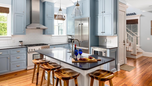 A modern kitchen with blue cabinets, a central island with stools, stainless steel appliances, and pendant lighting. - Family-Friendly Wild Dunes Home Just Steps from the Beach (Isle Of Palms)