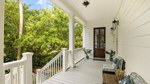 A covered porch with white railings, a wooden door, and potted plants. - Family-Friendly Wild Dunes Home Just Steps from the Beach (Isle Of Palms)