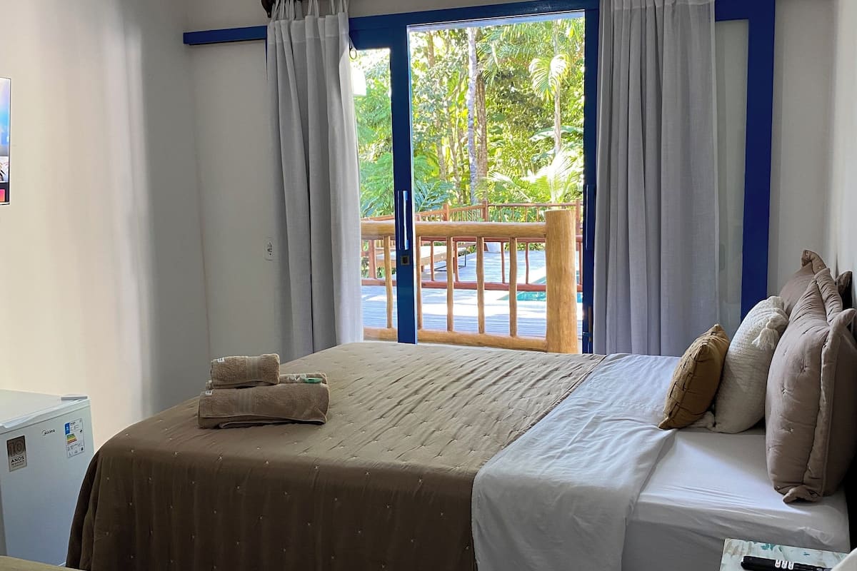 A hotel room with a bed, a desk, and a view of the outdoors.