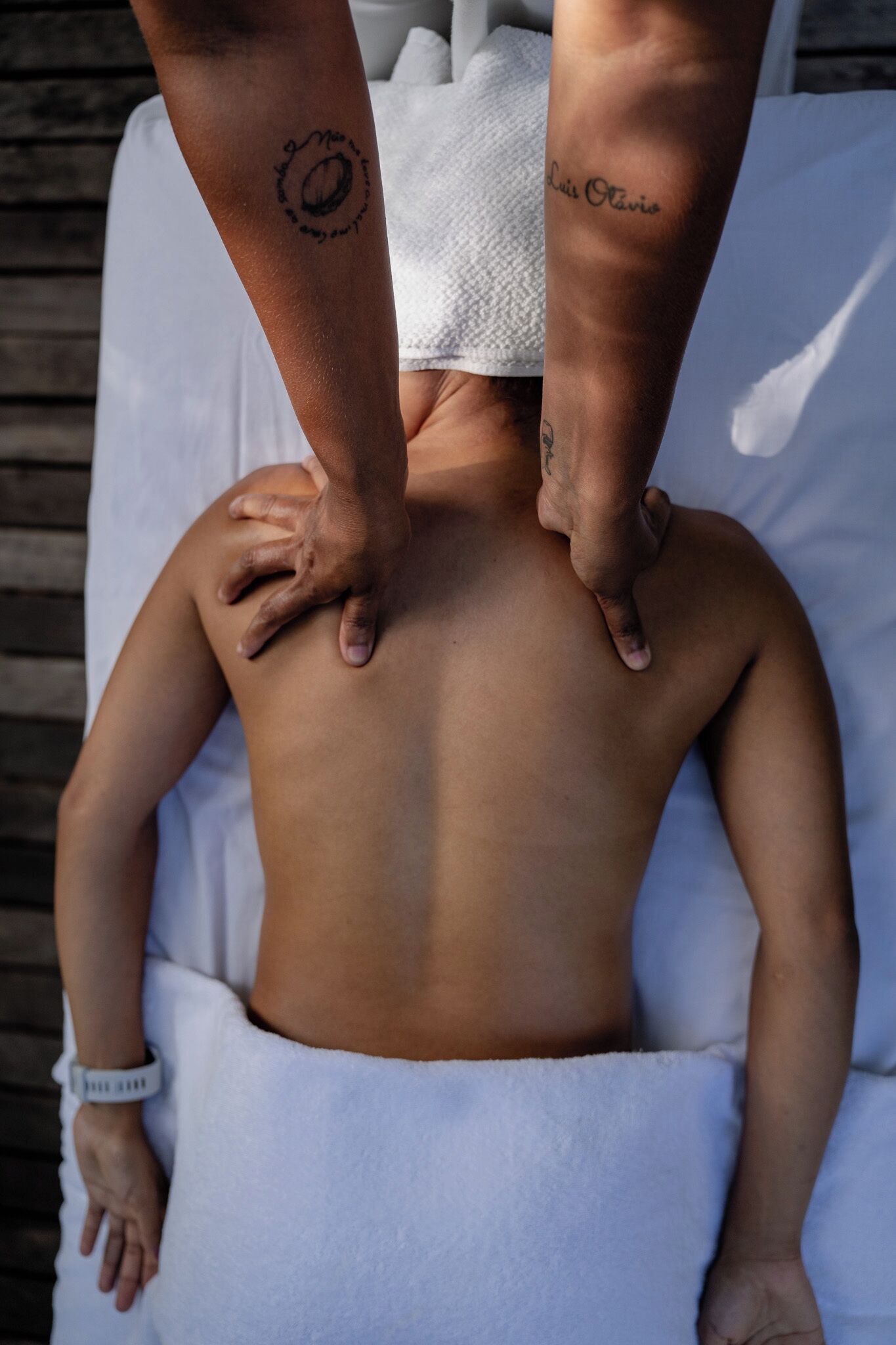A person lying on a bed with a towel, receiving a massage.