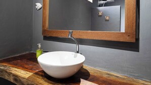 Une salle de bain avec un meuble-lavabo en bois, un lavabo blanc et un miroir avec un cadre en bois.