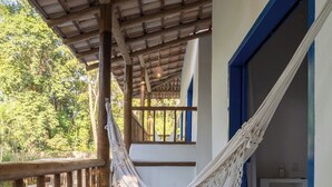 Un hamac sur un balcon donnant sur une piscine et une végétation luxuriante.