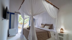 Une chambre à coucher avec un lit à baldaquin, une table de chevet avec une lampe et un téléviseur fixé au mur.