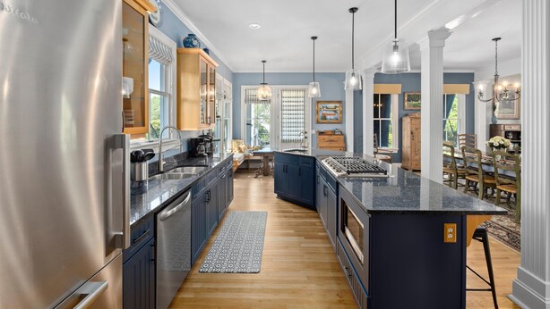 Una cocina moderna con un refrigerador de acero inoxidable, armarios azul oscuro y una encimera de granito.