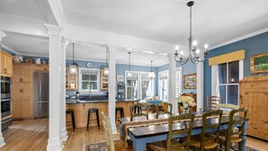 Una cocina amplia con armarios de madera, una isla central y un comedor con una mesa azul y sillas de madera.