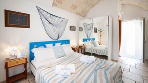 A hotel room with a bed, a nightstand, a mirror, and a stone ceiling.