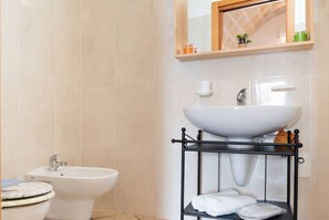 Ein Badezimmer mit integriertem Bidet, Waschbecken und einem Ablagefach mit Handtüchern.