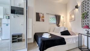 Un dormitorio moderno con cama, mesita de noche y zona de ducha de vidrio.