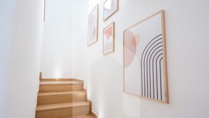 A staircase with wooden steps leading to a landing, where four framed artworks are hung on the wall.