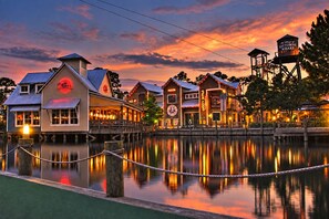 A waterfront property with multiple buildings, a dock, and a reflection in the water.