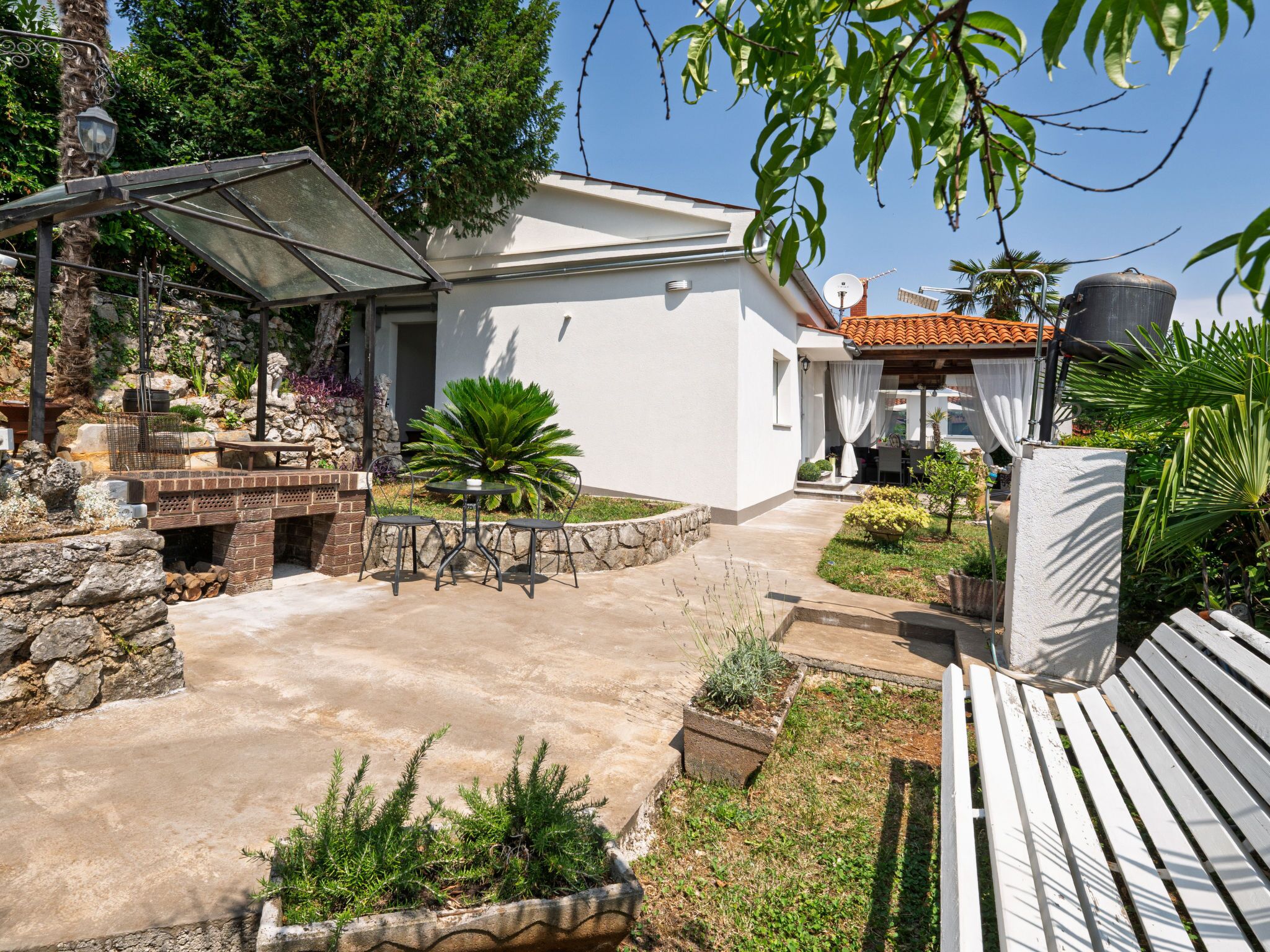 Una casa moderna con un patio, mobiliario exterior y un jardín.
