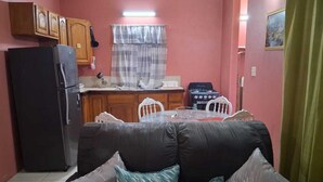 Una cocina compacta con refrigerador, estufa y mesa de comedor con sillas.