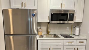 A modern kitchen with stainless steel appliances, white cabinetry, and a black rug.