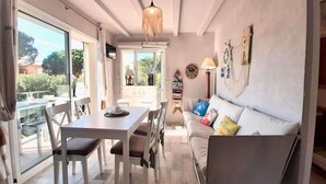 A modern living room with a dining area, large windows, and a cozy sofa. - Apartment in Calella near the Beach (Calella de Palafrugell, Llafranc)