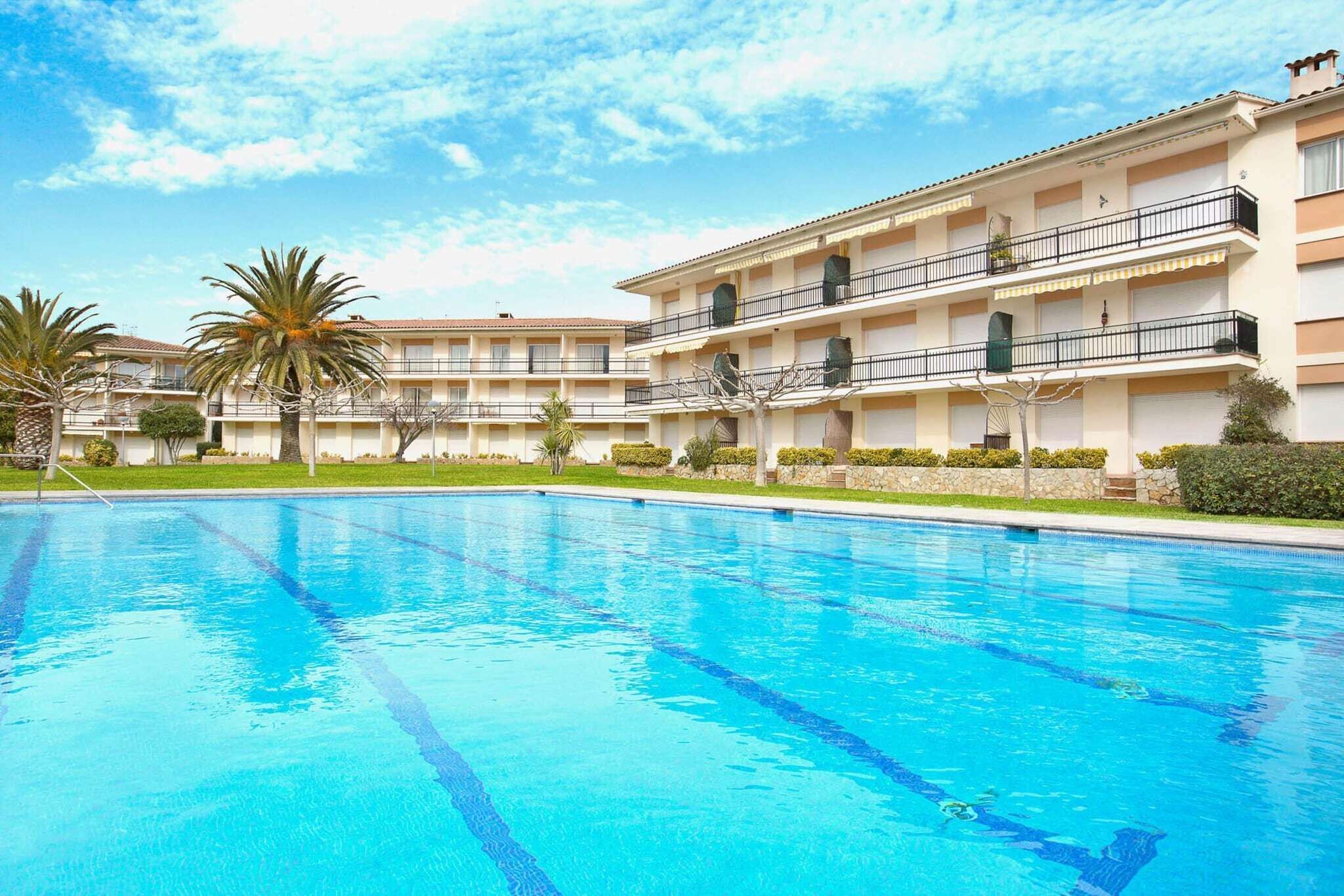 Ein Hotel mit Schwimmbad, mehreren Balkonen und Palmen.