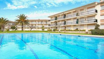 Ein Hotel mit Schwimmbad, mehreren Balkonen und Palmen.