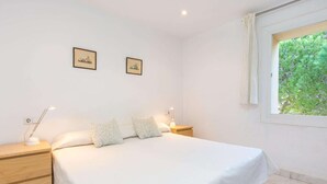 Une chambre à coucher avec un grand lit, deux tables de chevet, deux lampes fixées au mur et deux tableaux encadrés.