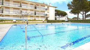 Una piscina amb una escala metàl·lica, envoltada d'un edifici amb balcons i una tanca.