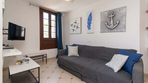 A living room with a sofa, a flat-screen TV, a small table, and artwork on the wall. - Parque Santiago II - 2 Bed Sea View (Playa de Las Americas)