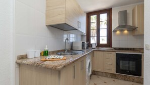 A kitchen with a granite countertop, stainless steel appliances, wooden cabinets, and a window with a view. - Parque Santiago II - 2 Bed Sea View (Playa de Las Americas)