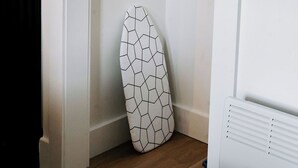 Eine Ecke eines Raumes mit weißer Wand, Holzboden und weißem Heizkörper.