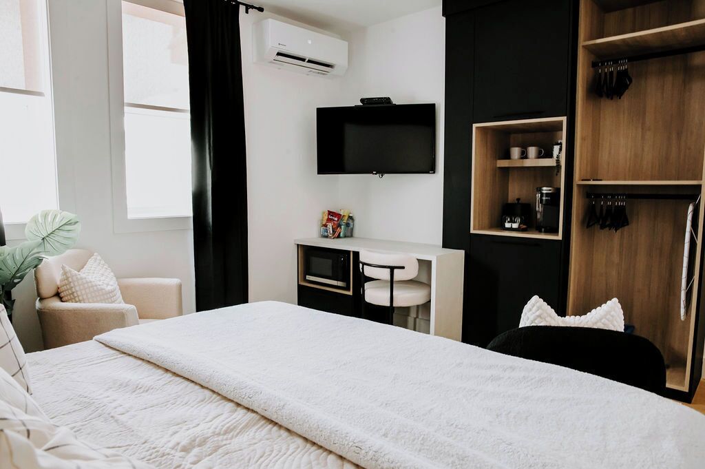 Ett modernt hotellrum med en säng, ett skrivbord, en TV och en garderob.