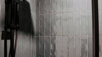 A shower area with a black rain showerhead and a handheld showerhead mounted on the wall.