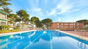 En rektangulär swimmingpool med klart, blått vatten, omgiven av en kakelbeklädd poolterrass och metallräcken.
