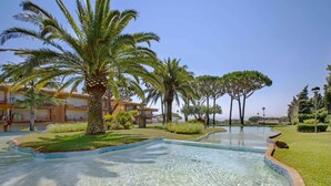 Une piscine entourée de palmiers, avec un bâtiment en arrière-plan.