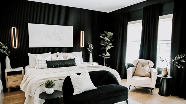 A modern bedroom with a black and white color scheme, featuring a large bed, a black bench, a white armchair, and a bedside table with a vase. - M2 - Spacious King Room # 3 (Dalhousie)