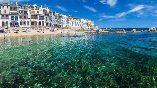 Une ville côtière aux eaux cristallines, aux bâtiments blancs et à la plage de sable fin.