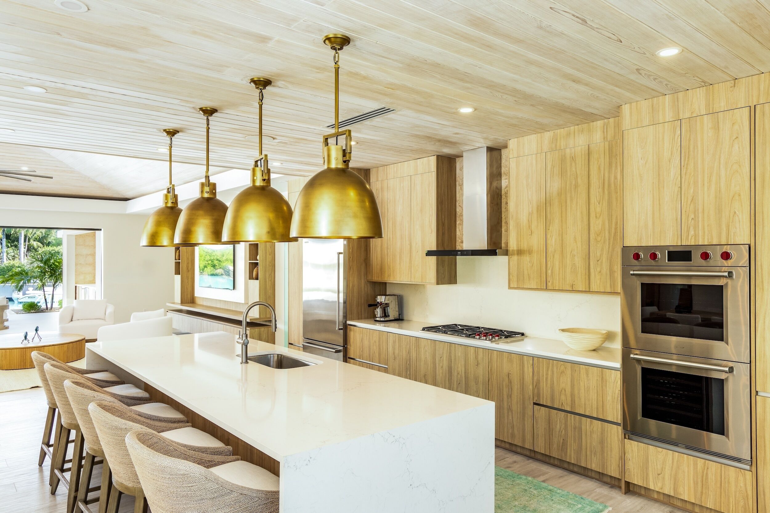 Una cocina moderna con armarios de madera, una isla de mármol blanco y electrodomésticos de acero inoxidable.