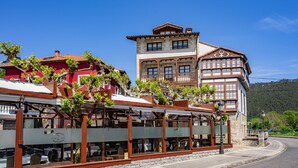 A building with a restaurant on the ground floor, a balcony with plants, and a stone facade.
