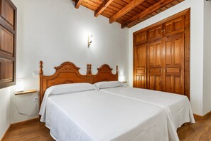 Un lit double avec une tête de lit en bois, une table de chevet avec une lampe et une grande armoire en bois.
