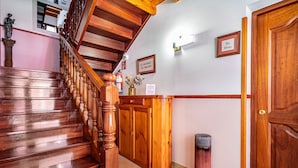 A wooden staircase with a handrail, a wooden reception desk, a door, and a wall-mounted light fixture.