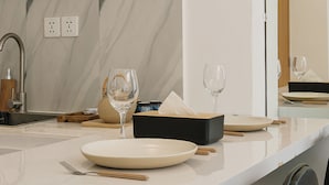 Una cocina moderna con salpicadero de mármol, horno empotrado y comedor con mesa y sillas blancas.