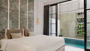 Un dormitorio con una cama grande, vistas a una piscina y una pared de piedra.