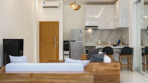Cozy retreat with a wooden bed, bench, and compact kitchen featuring a refrigerator, oven, and stove.