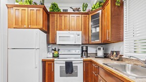 Une cuisine avec des meubles de rangement en bois, un réfrigérateur blanc, une cuisinière et un évier.