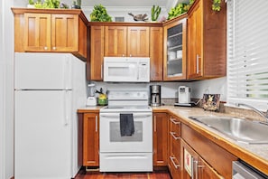 A kitchen with wooden cabinets, a white refrigerator, a stove, and a sink.