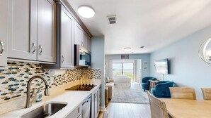 Una cocina moderna con un salpicadero de diseño, una zona de comedor con mesa de madera y vistas a través de una puerta de vidrio.