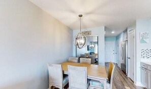 A dining area with a wooden table and chairs, a chandelier, and a sign that reads "BEACH".