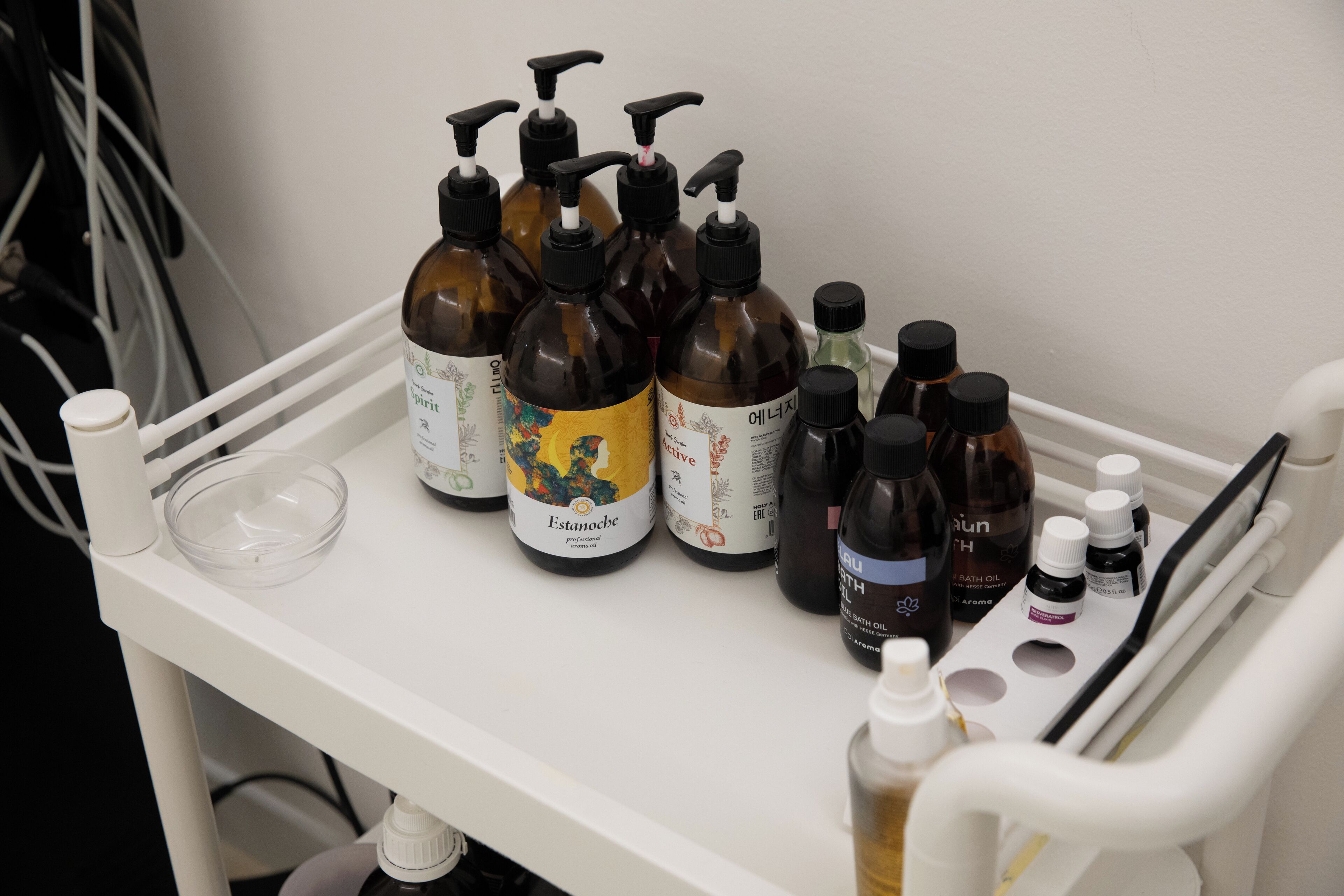 A white tray with various bottles of bath products, including Estanoche and bath oils, on a white surface.