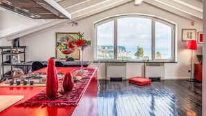 Eine moderne Küche mit roter Arbeitsplatte, einem großen Fenster mit Meerblick und einem roten Teppich.