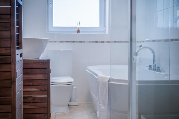 A bathroom with a toilet, a bathtub, and a shower area.
