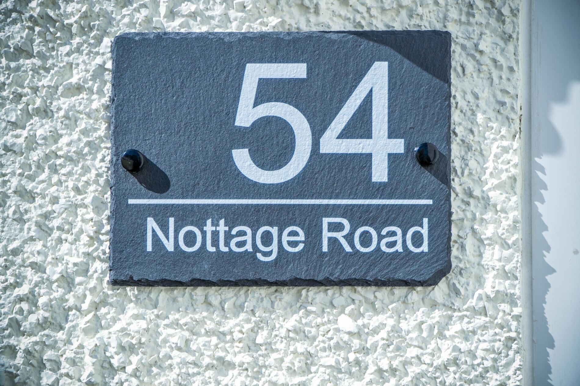 A house number sign for Nottage Road, displaying the number 54.